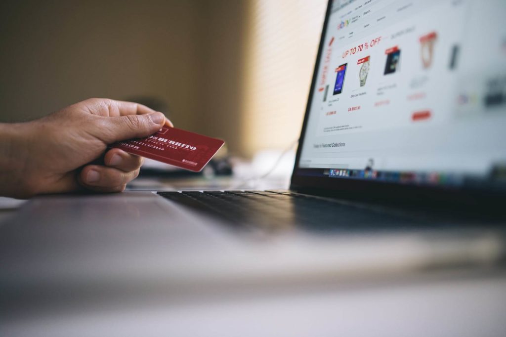 Man holding credit card in front of the laptop