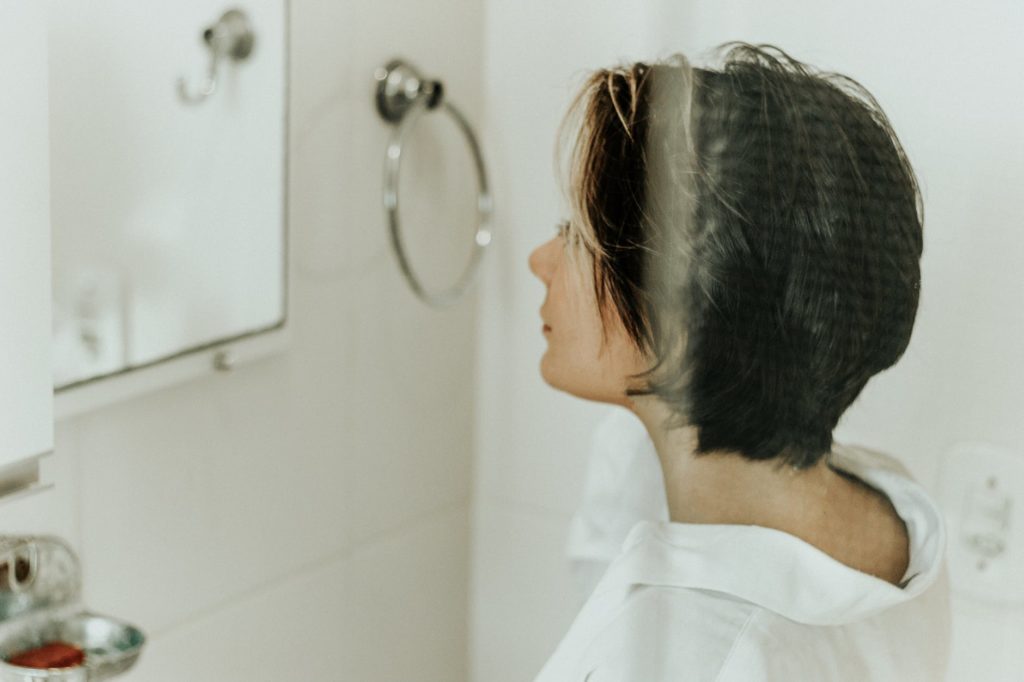 Woman with Brown Hair Looking into a Bathroom Mirror