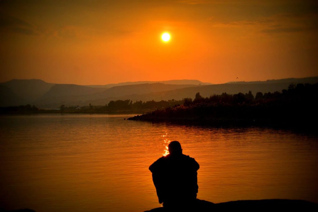 Man watching the sunrise over a lake